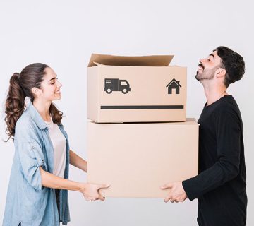 A woman and a man holding cardboard boxes with moving symbols, standing in front of a plain white background.