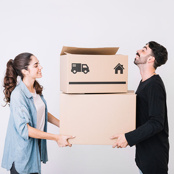 A woman and a man holding cardboard boxes with moving symbols, standing in front of a plain white background.